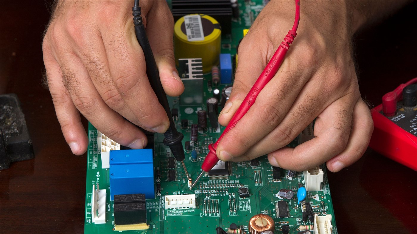 Electronic circuit board undergoing electrical testing with a multimeter